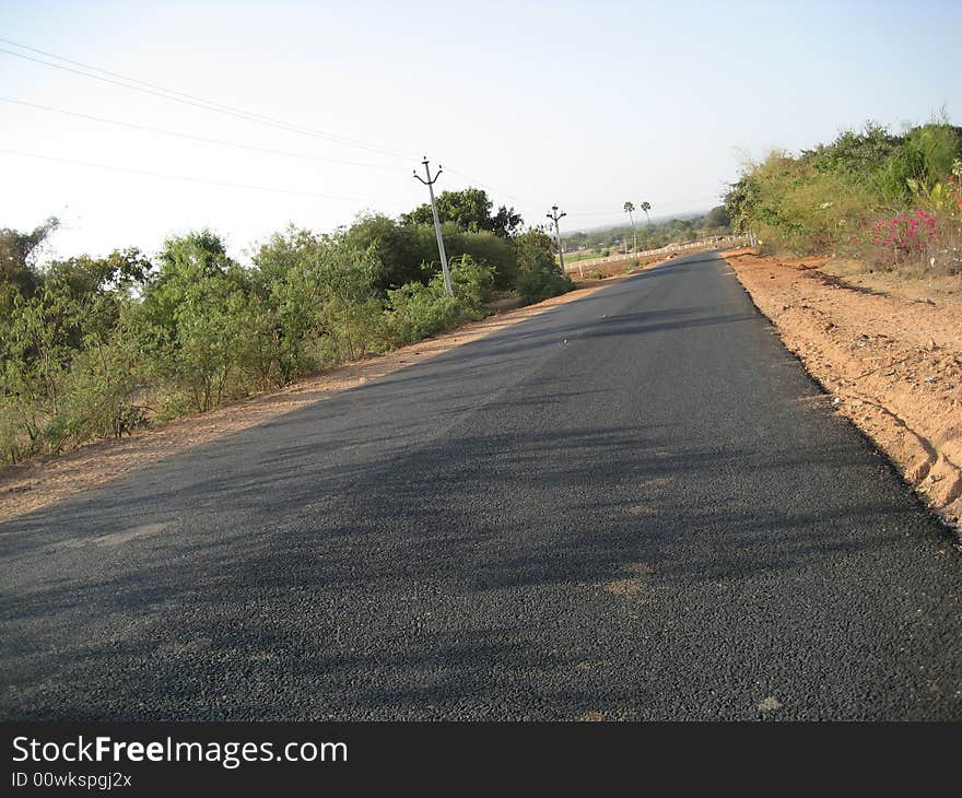 Indian tar road with trees in both sides with the blue sky. Indian tar road with trees in both sides with the blue sky.