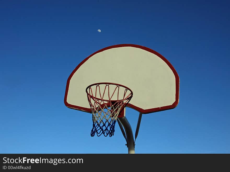 Basketball backboard against a blue sky with moon. Basketball backboard against a blue sky with moon.