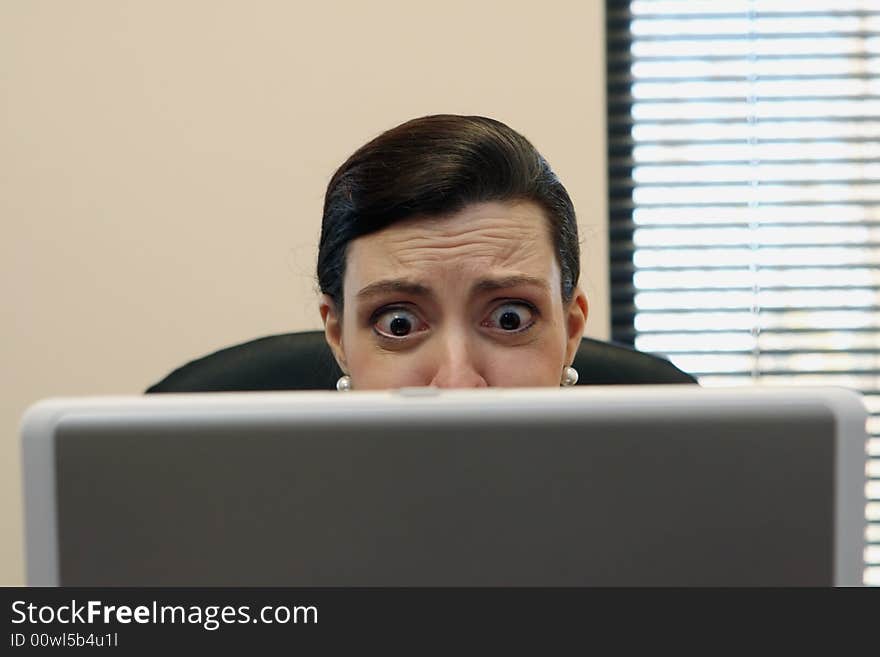 Businesswoman sitting at her desk behind her laptop screen. Businesswoman sitting at her desk behind her laptop screen