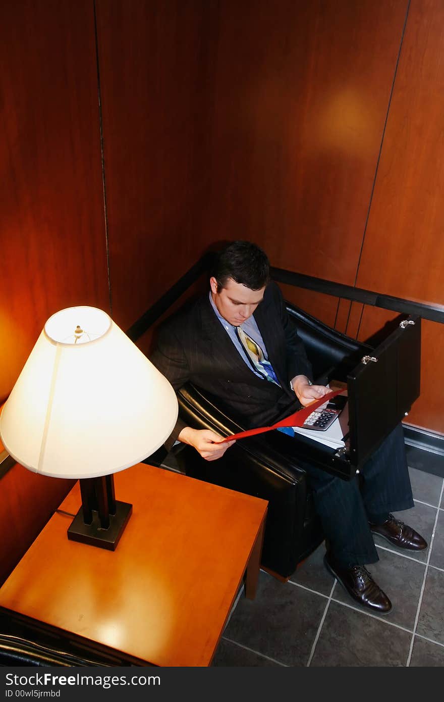 Businessman waiting in an office lobby with his briefcase open. Businessman waiting in an office lobby with his briefcase open