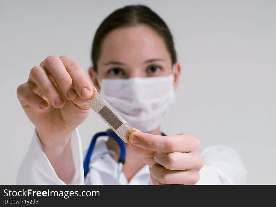 An isolated head shot of a doctor/nurse holding out a bandage, as if to put it on patient. An isolated head shot of a doctor/nurse holding out a bandage, as if to put it on patient.