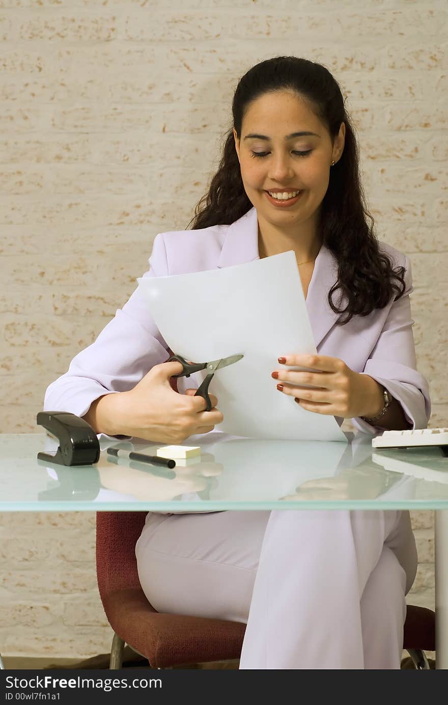 An isolated shot of a businesswoman cutting papers.