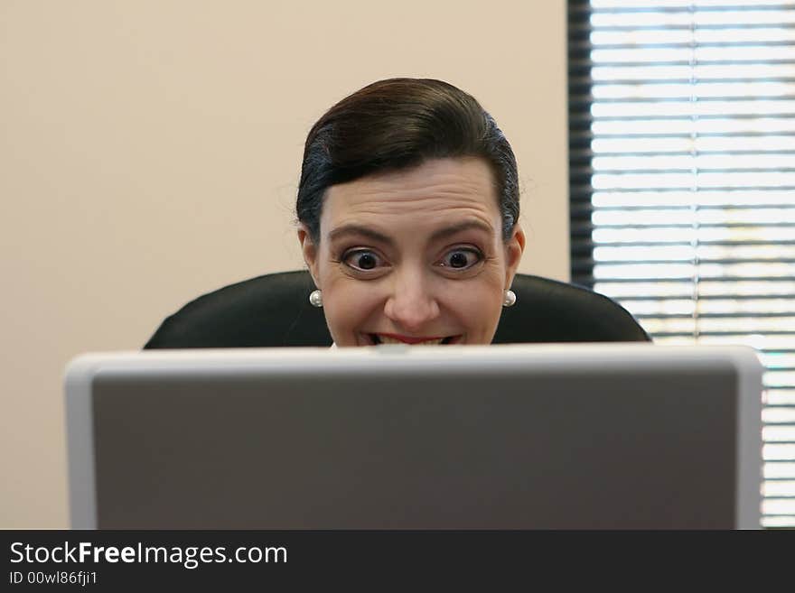 Businesswoman sitting at her desk behind her laptop screen. Businesswoman sitting at her desk behind her laptop screen