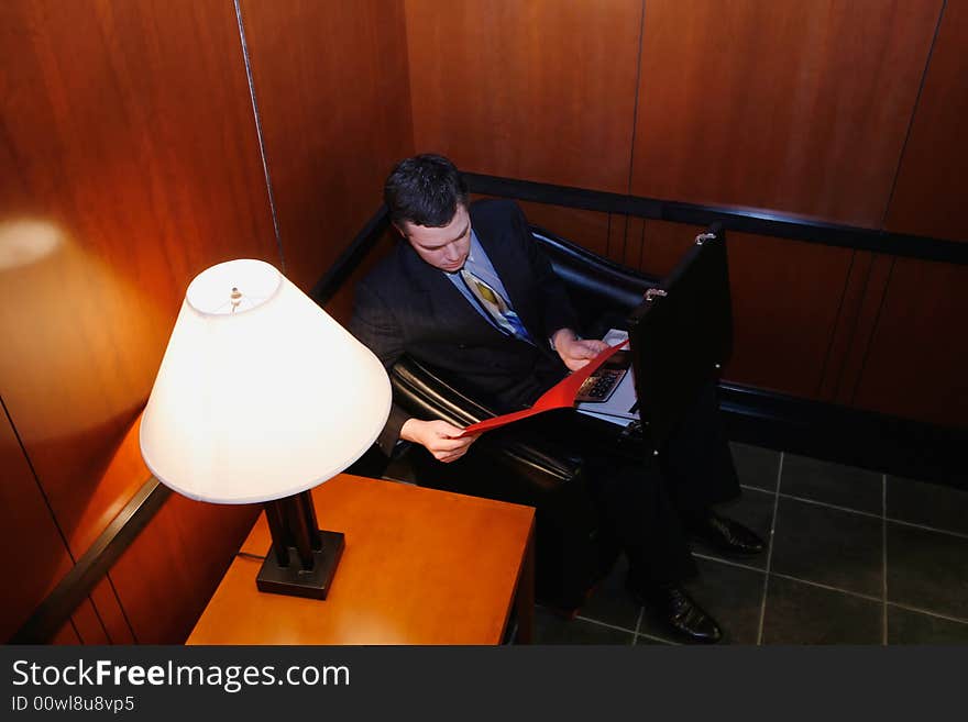 Businessman waiting in an office lobby with his briefcase open. Businessman waiting in an office lobby with his briefcase open