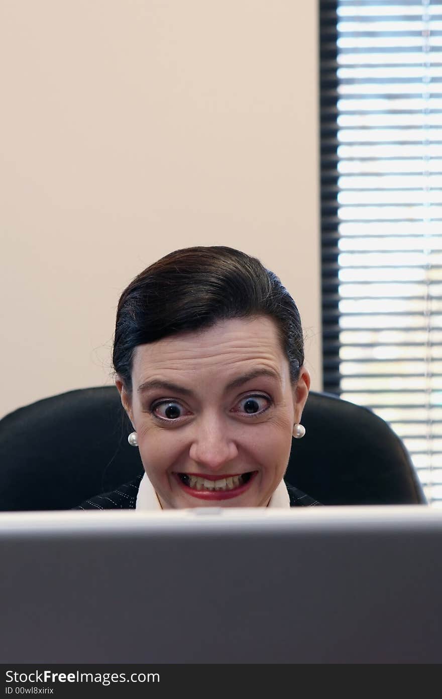 Businesswoman sitting at her desk behind her laptop screen. Businesswoman sitting at her desk behind her laptop screen