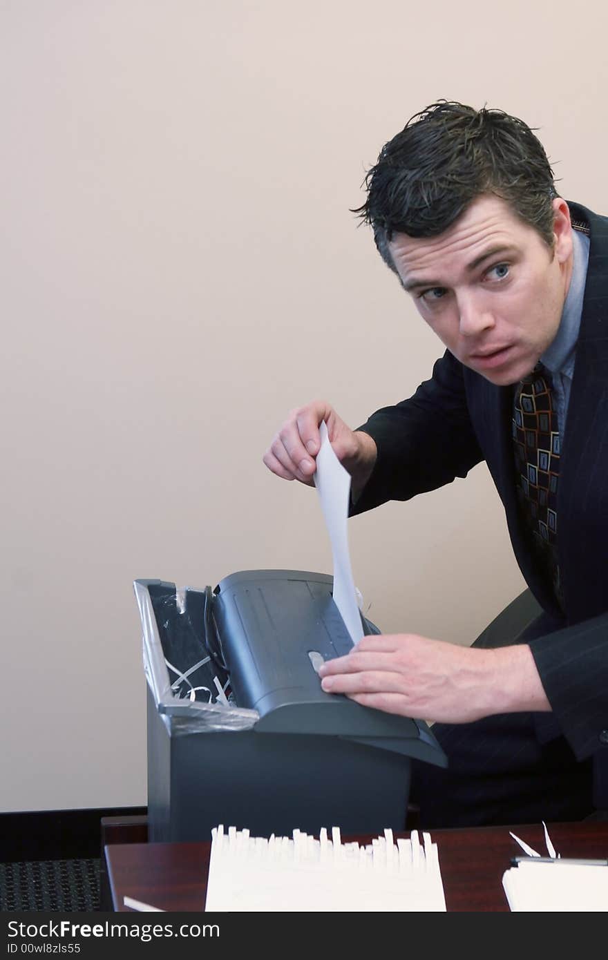 Caucasian businessman furtively shredding documents at his desk. Caucasian businessman furtively shredding documents at his desk