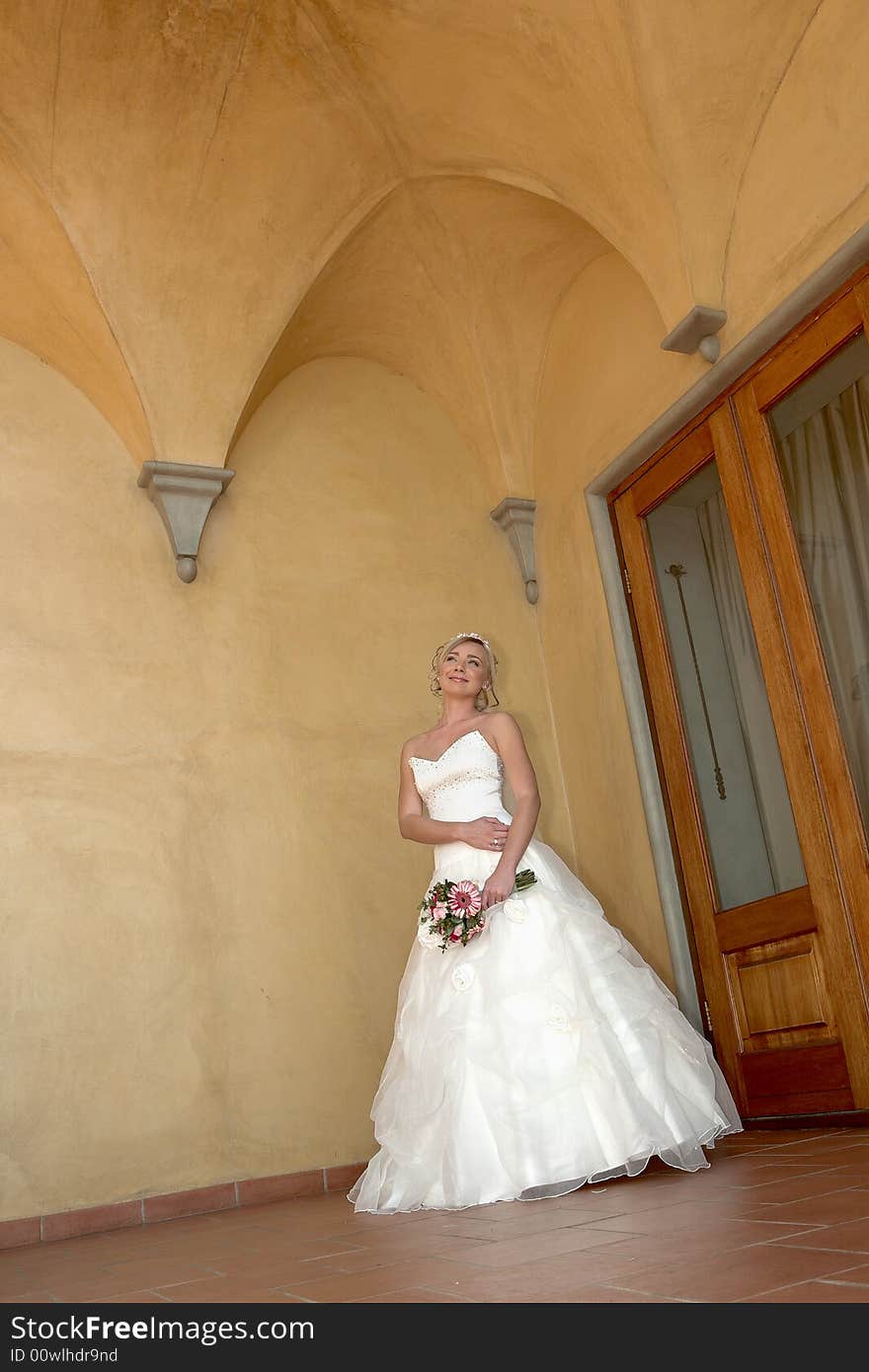 A bride standing under arch in her dress. A bride standing under arch in her dress