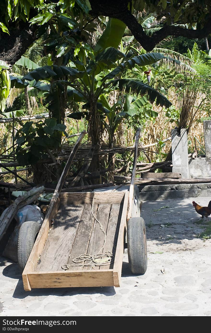 A wheelbarrow parked in the shade under a few trees