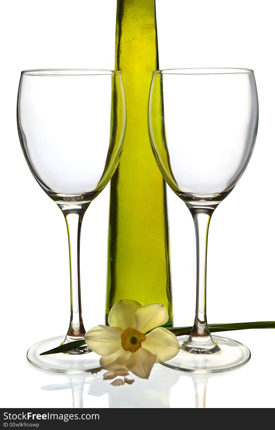 Wine bottle and two empty glasses with daffodil against a white background. Wine bottle and two empty glasses with daffodil against a white background