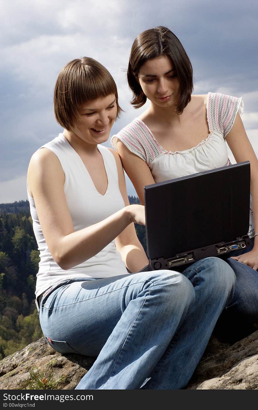 Two friends with laptop on a rock. Two friends with laptop on a rock