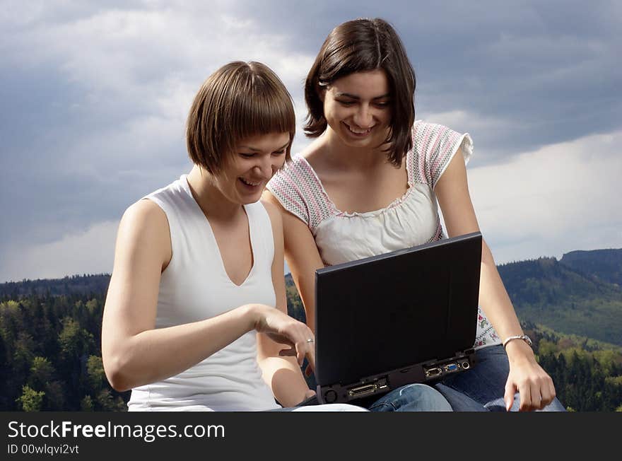 Two friends with laptop on a rock. Two friends with laptop on a rock