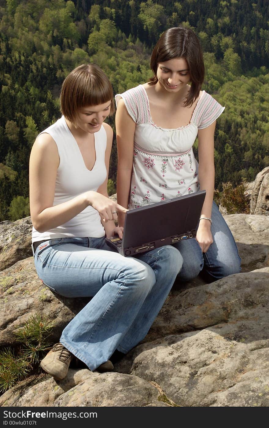 Two friends with laptop on a rock. Two friends with laptop on a rock