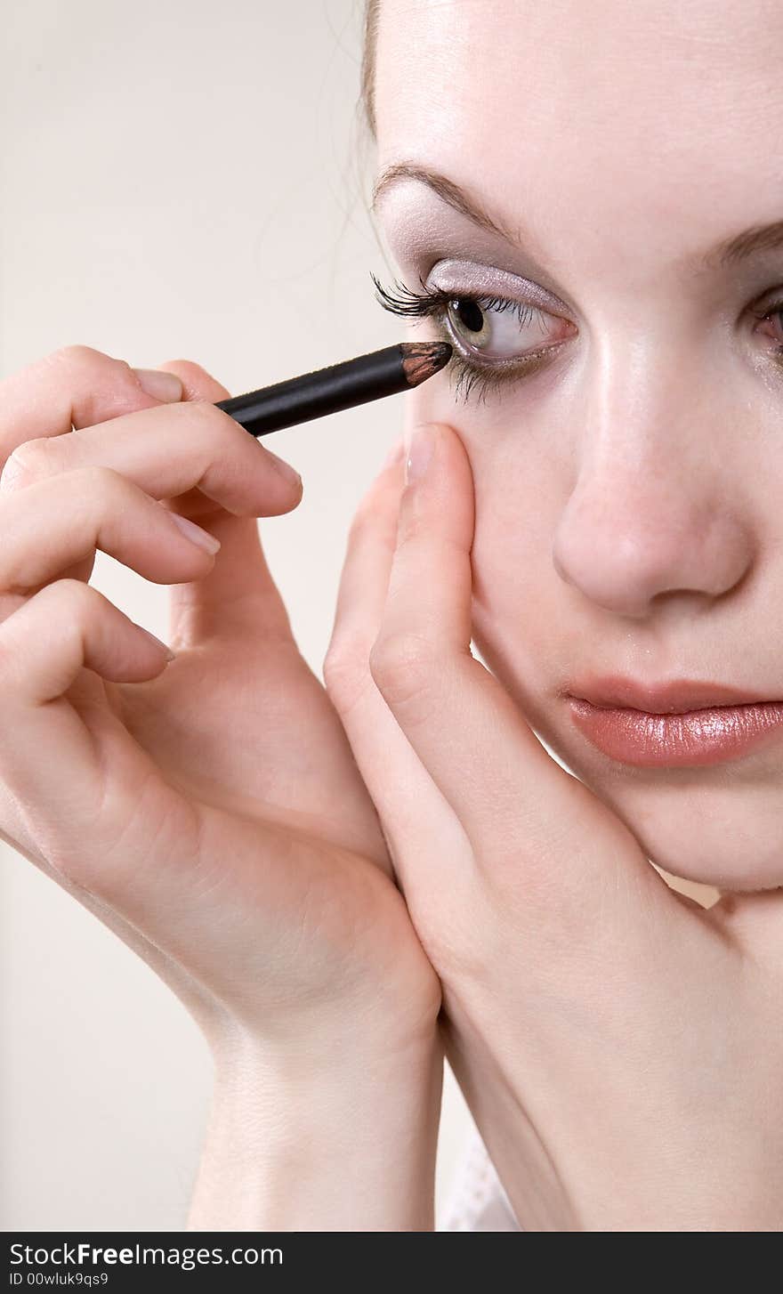 Young caucasian model applying cosmetics on her face. Young caucasian model applying cosmetics on her face