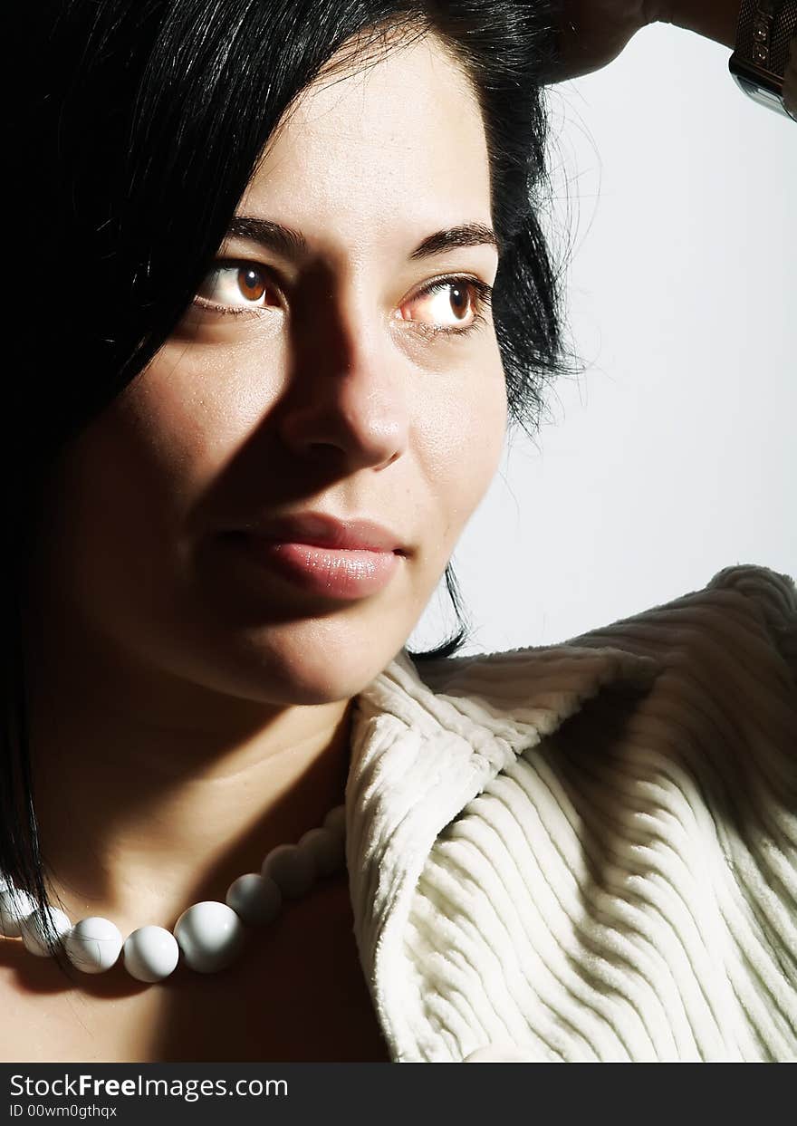 A high-key portrait about an attractive trendy lady with black hair who is looking at something and she has a glamorous look. She is wearing a white coat and a white necklace. A high-key portrait about an attractive trendy lady with black hair who is looking at something and she has a glamorous look. She is wearing a white coat and a white necklace.