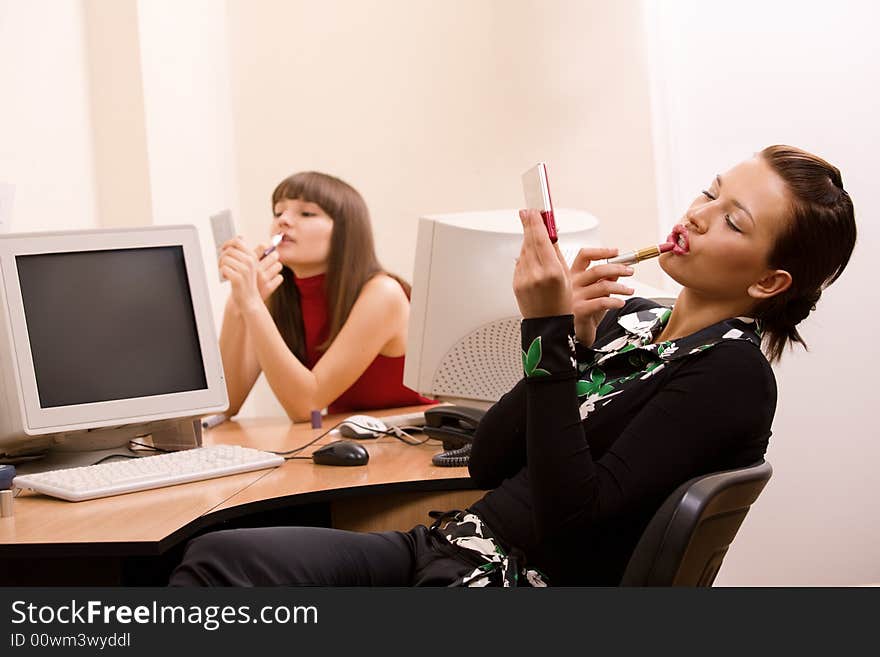 Young beautiful women applying make-up at office