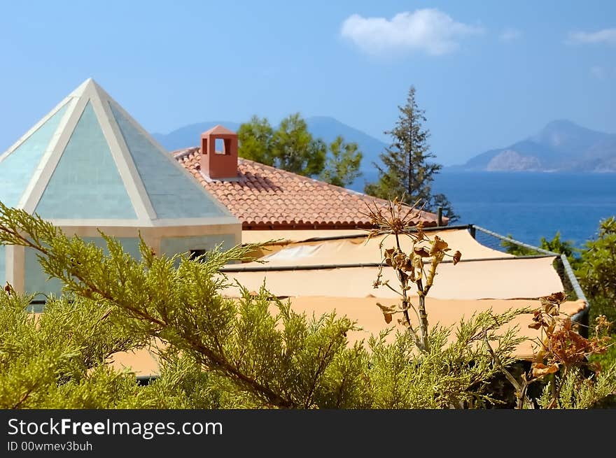 View on sea and mountains over roofs of coastal hotel