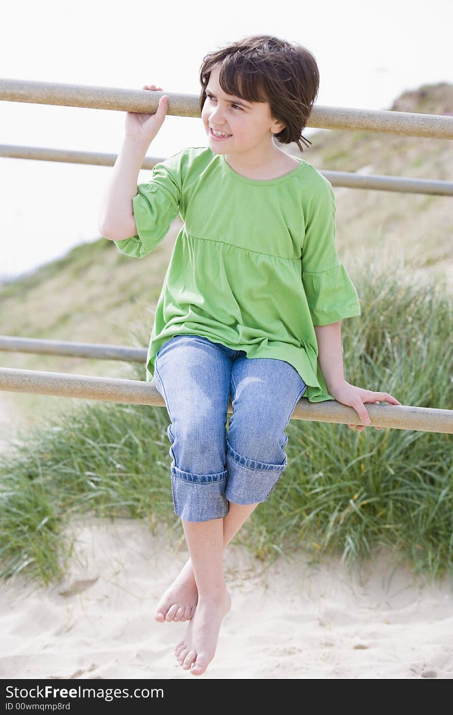 Young child sitting on railings by the beach. Young child sitting on railings by the beach