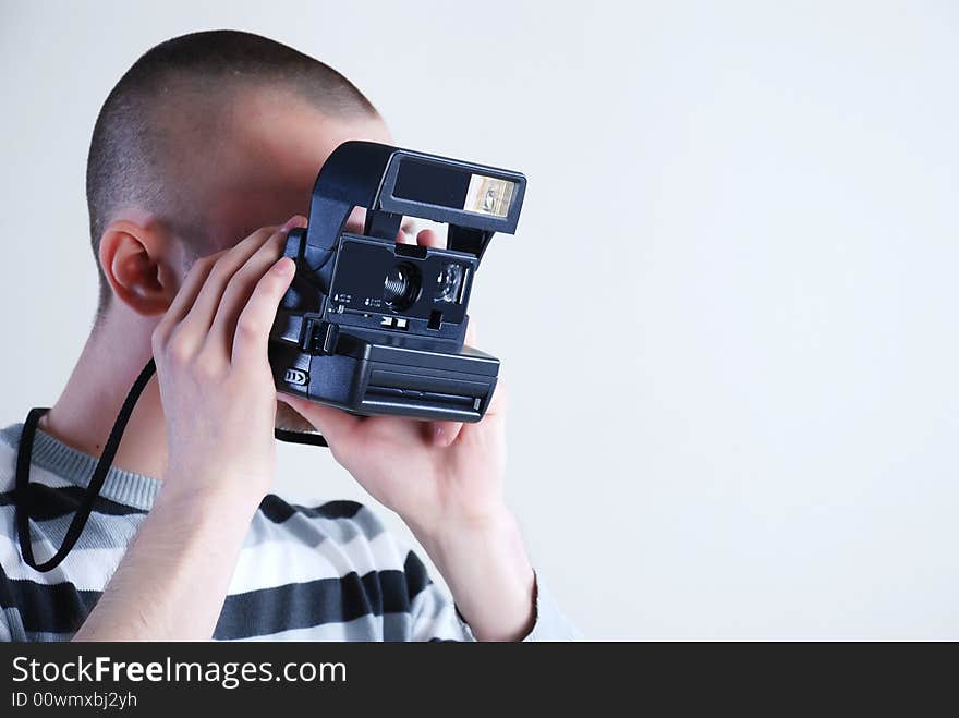 Young man photographer at white background with camera