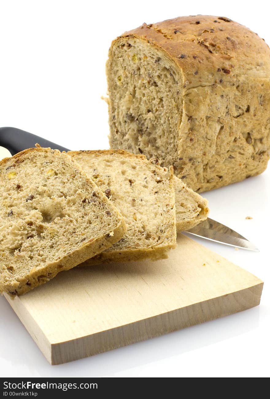 Fresh sliced whole grain bread on wooden board with knife, white background. Fresh sliced whole grain bread on wooden board with knife, white background