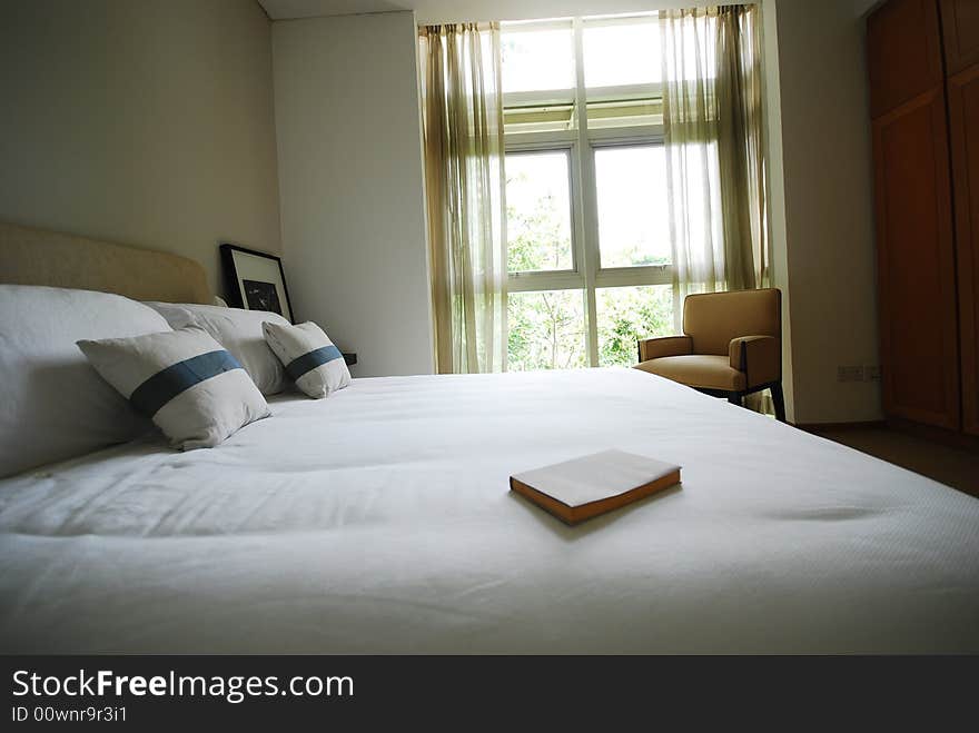 Book on the edge of a neatly made bed. Book on the edge of a neatly made bed.