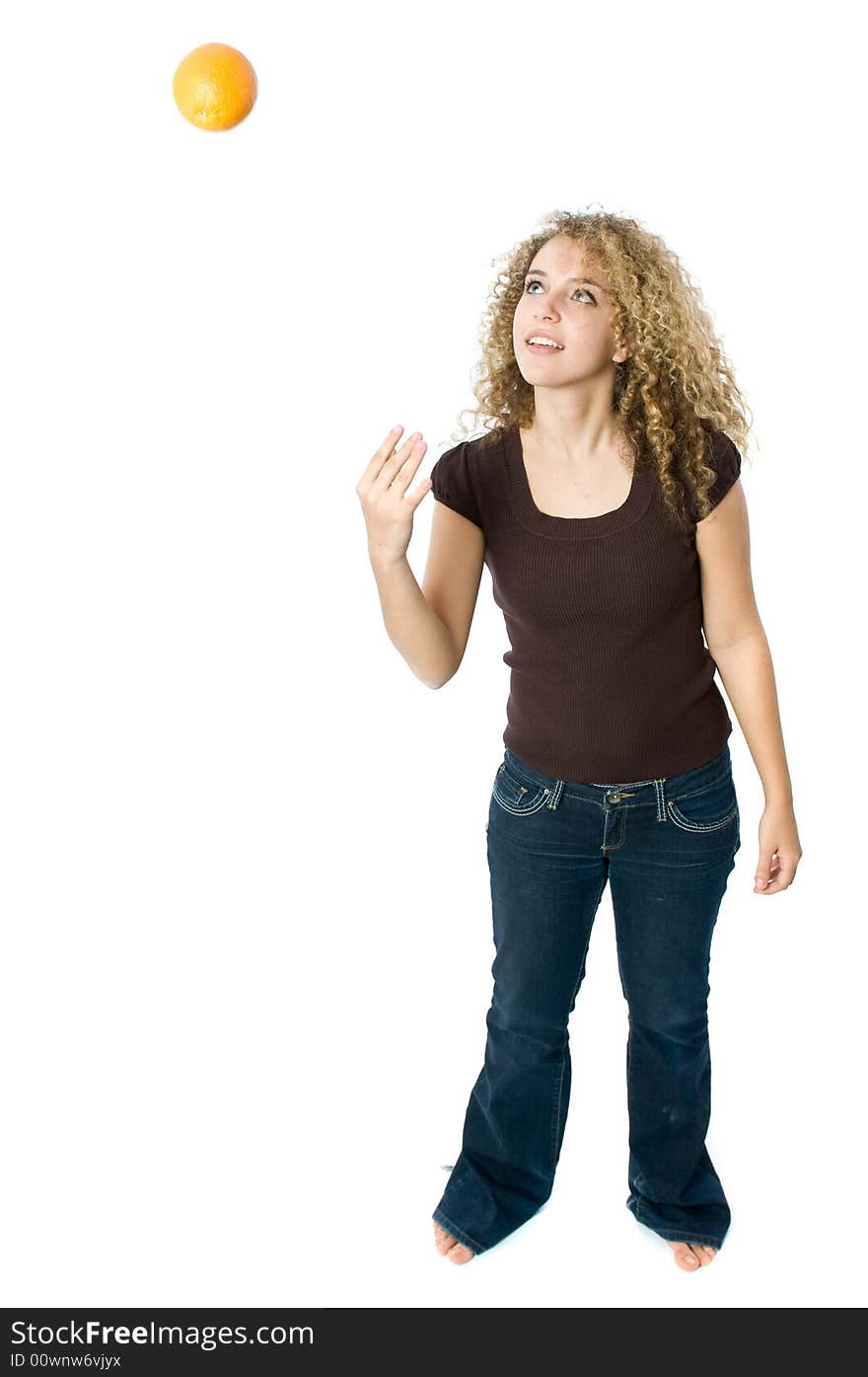 A beautiful young women throwing an orange up and down. A beautiful young women throwing an orange up and down