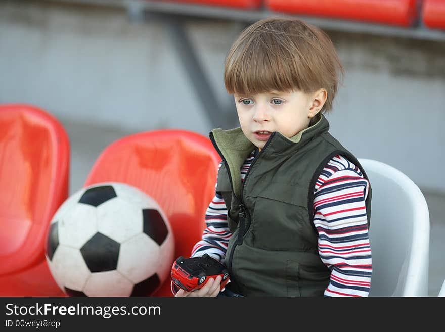 The boy with a toy on empty tribunes of stadium. The boy with a toy on empty tribunes of stadium