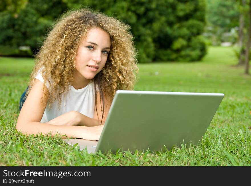 A beautiful young woman using a portable computer outside. A beautiful young woman using a portable computer outside