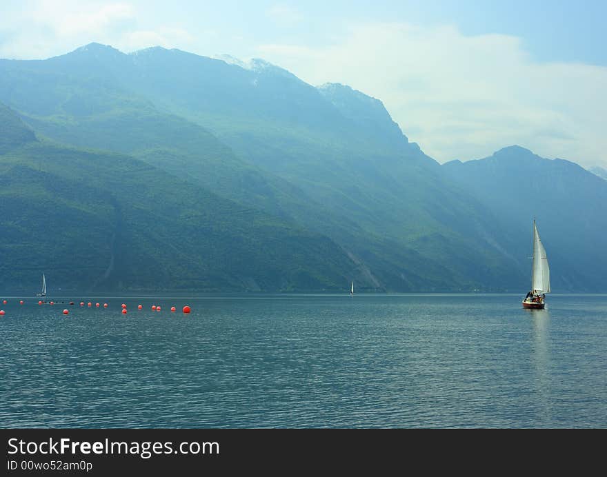 Sailboat on Garda lake early hazy morning