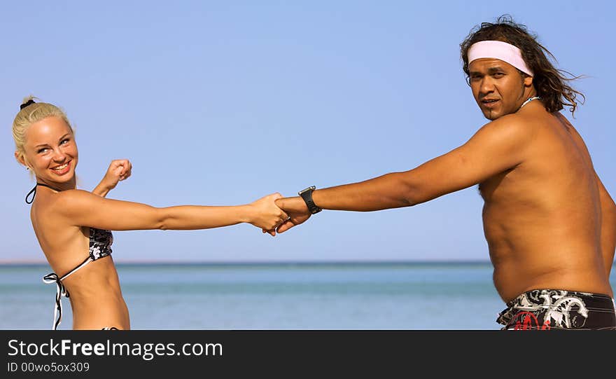 A young couple running on the beach in summer. A young couple running on the beach in summer