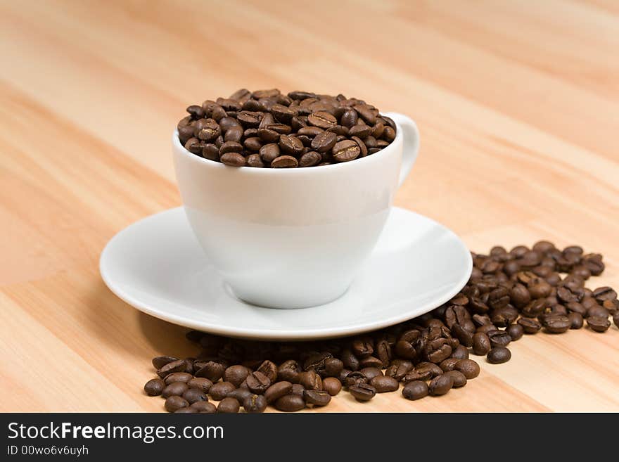 Cup with coffee beans on hardwood floor