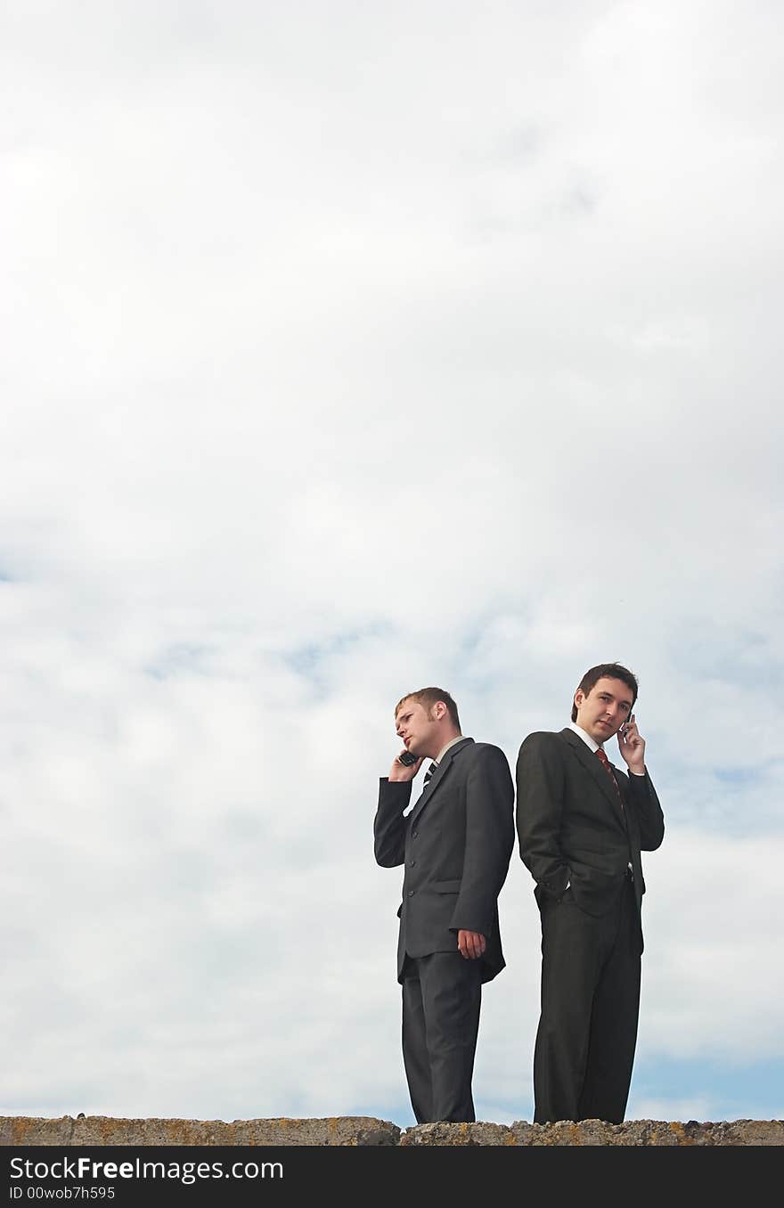 Businessmen talking by phone under the skies