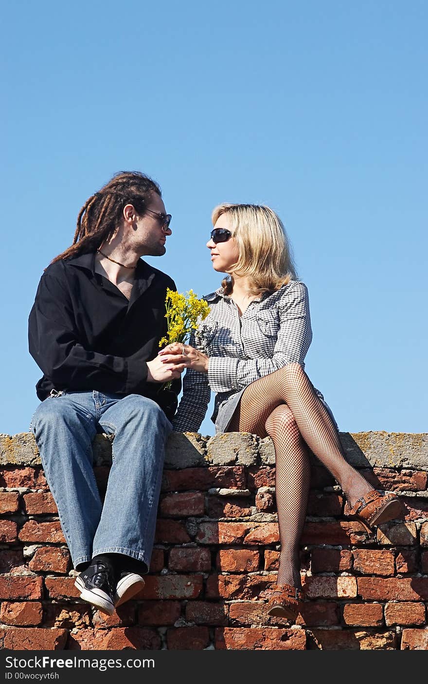 Couple sitting with flowers under the sky