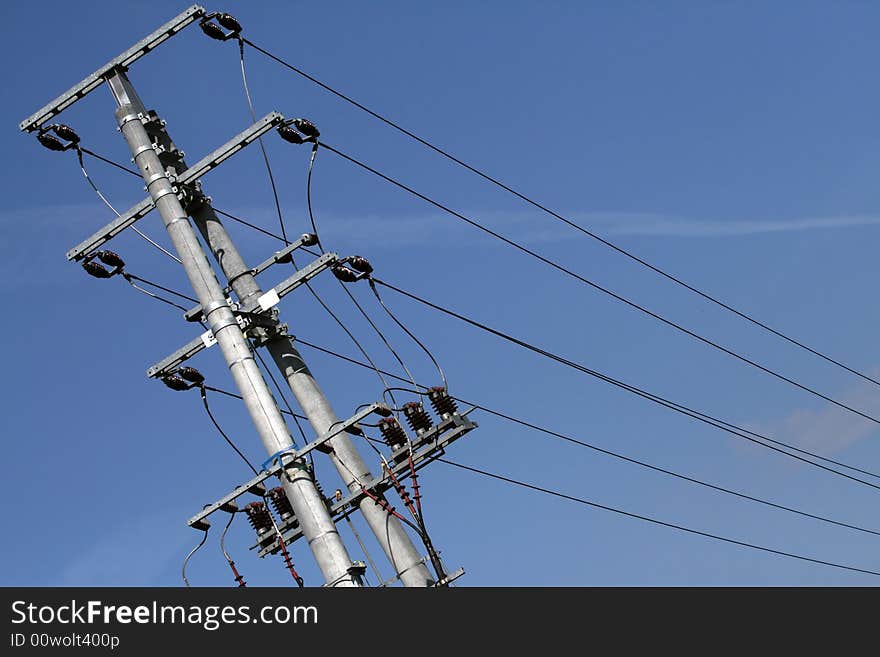 Top of the electriciti pylon over blue sky.