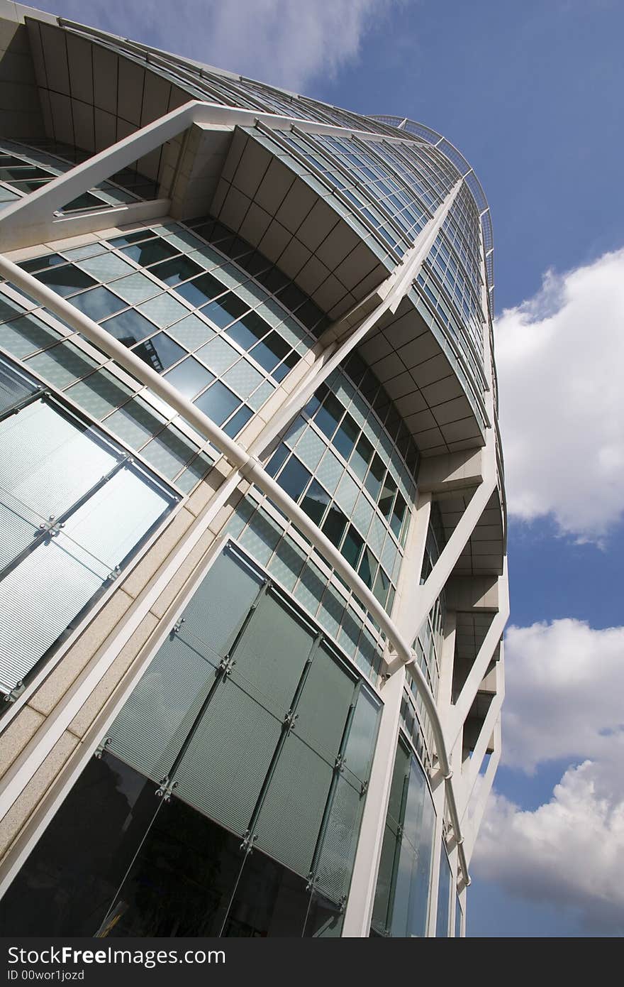 Looking upward along a round office building scraping the blue sky with clouds. Looking upward along a round office building scraping the blue sky with clouds