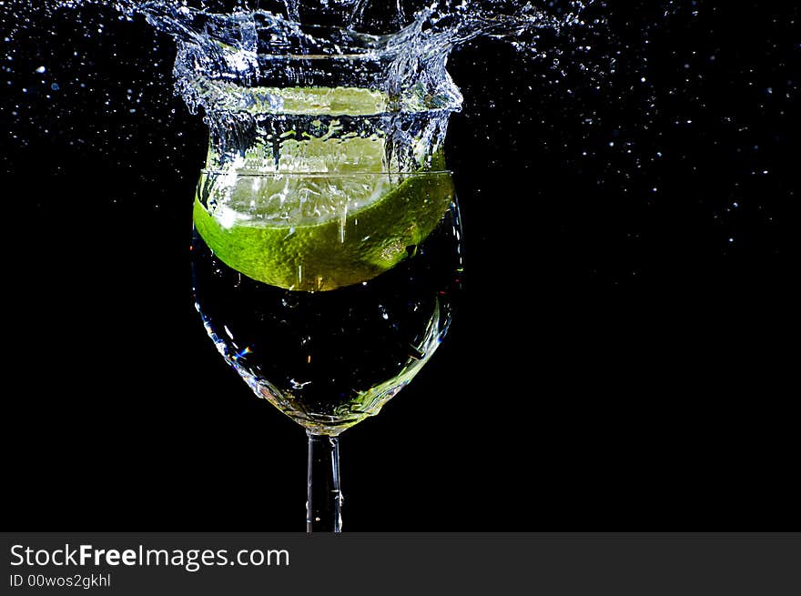 A peace of lemon falling in a glas with water. A peace of lemon falling in a glas with water