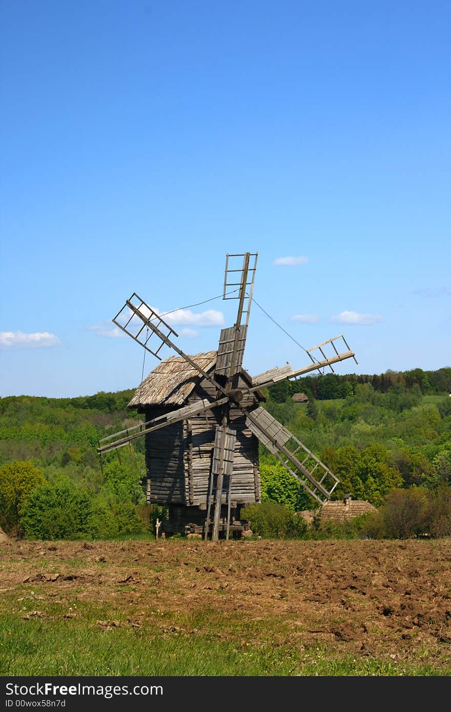 Windmill with fresh green grass and clear blue sky