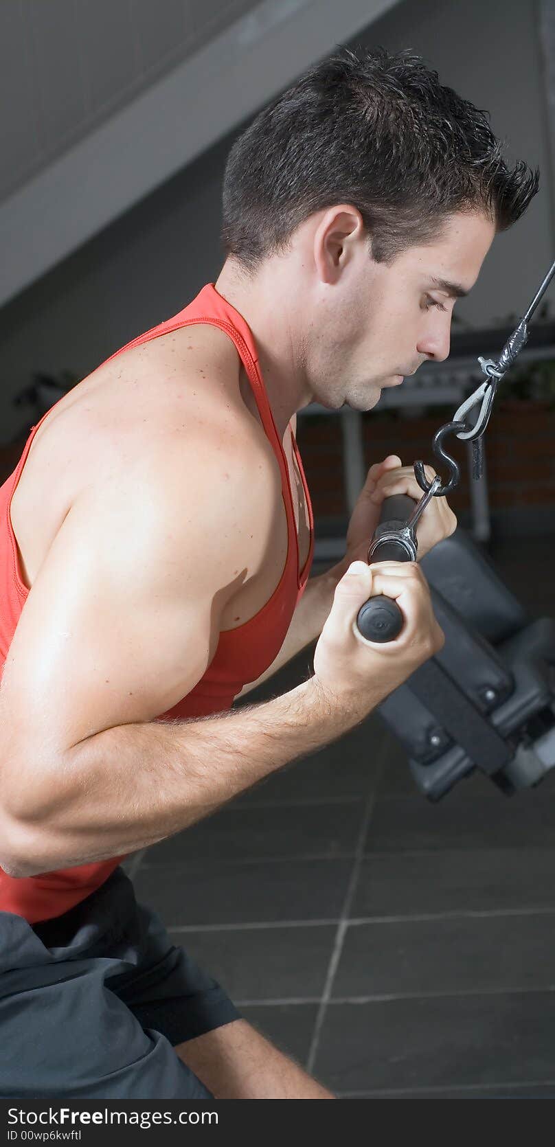 A side-shot of a male weightlifter doing pulldowns.