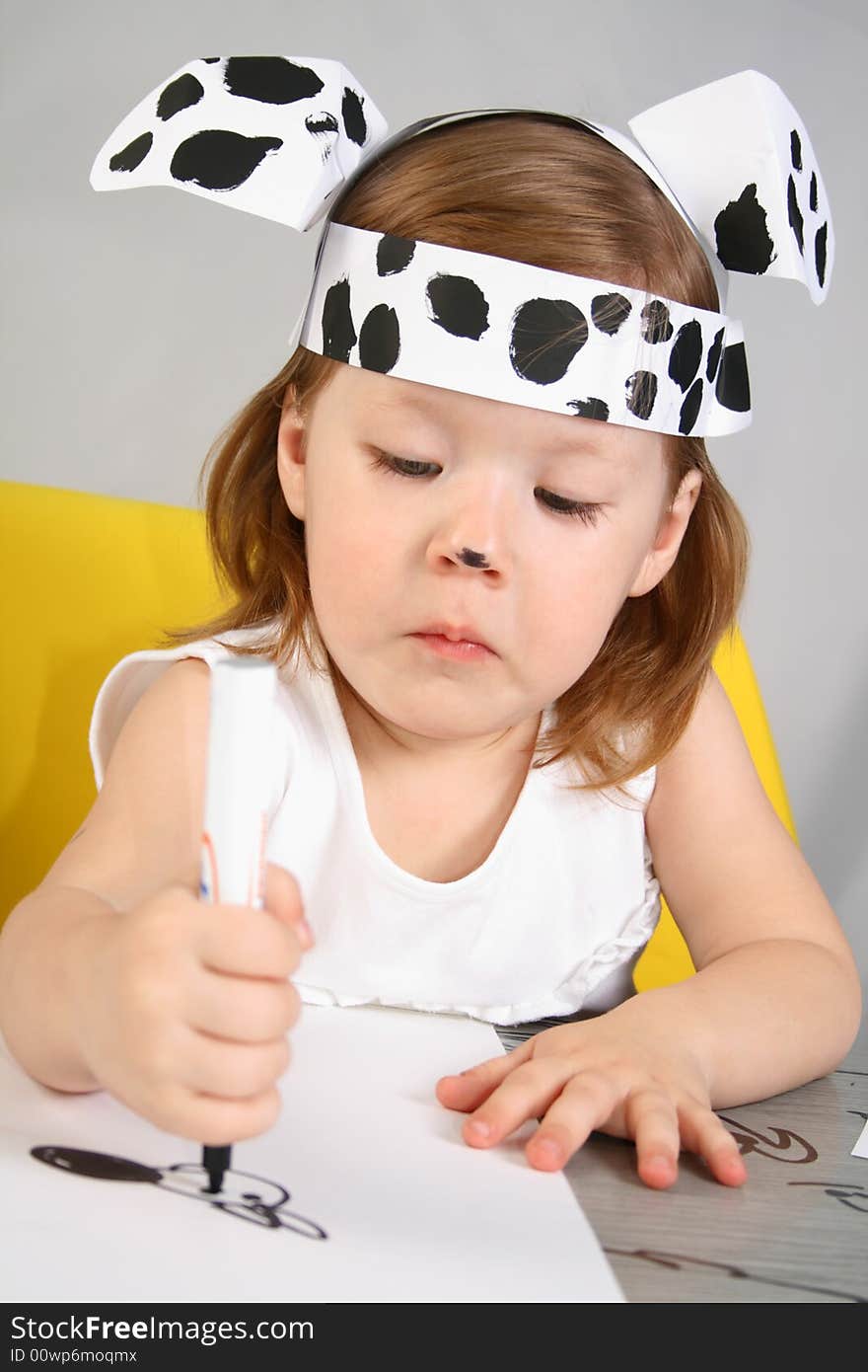 The small girl with dalmatian mask sketches the dog