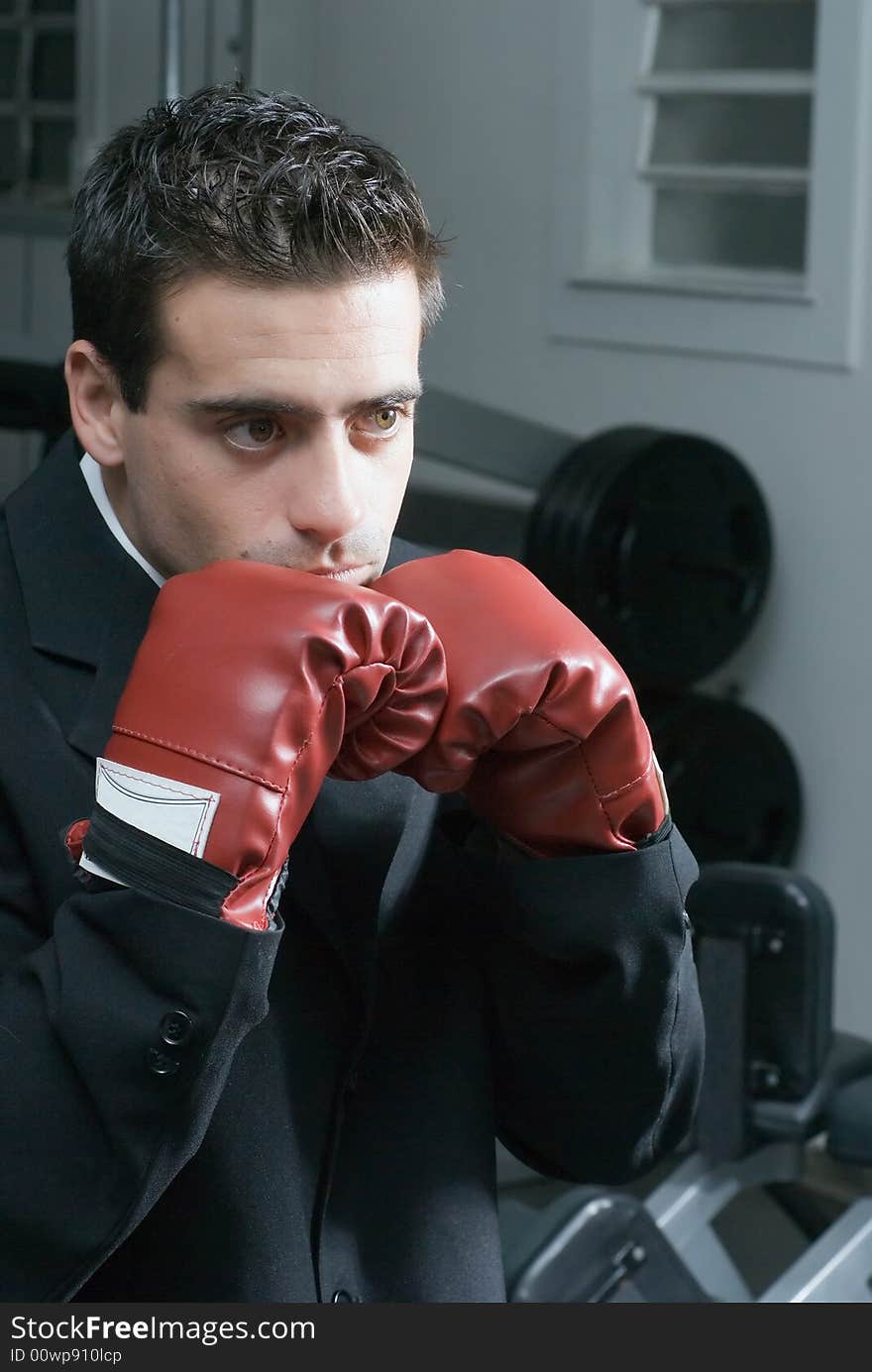 Attractive young businessman with his boxing gloves up in a ready stance. Attractive young businessman with his boxing gloves up in a ready stance