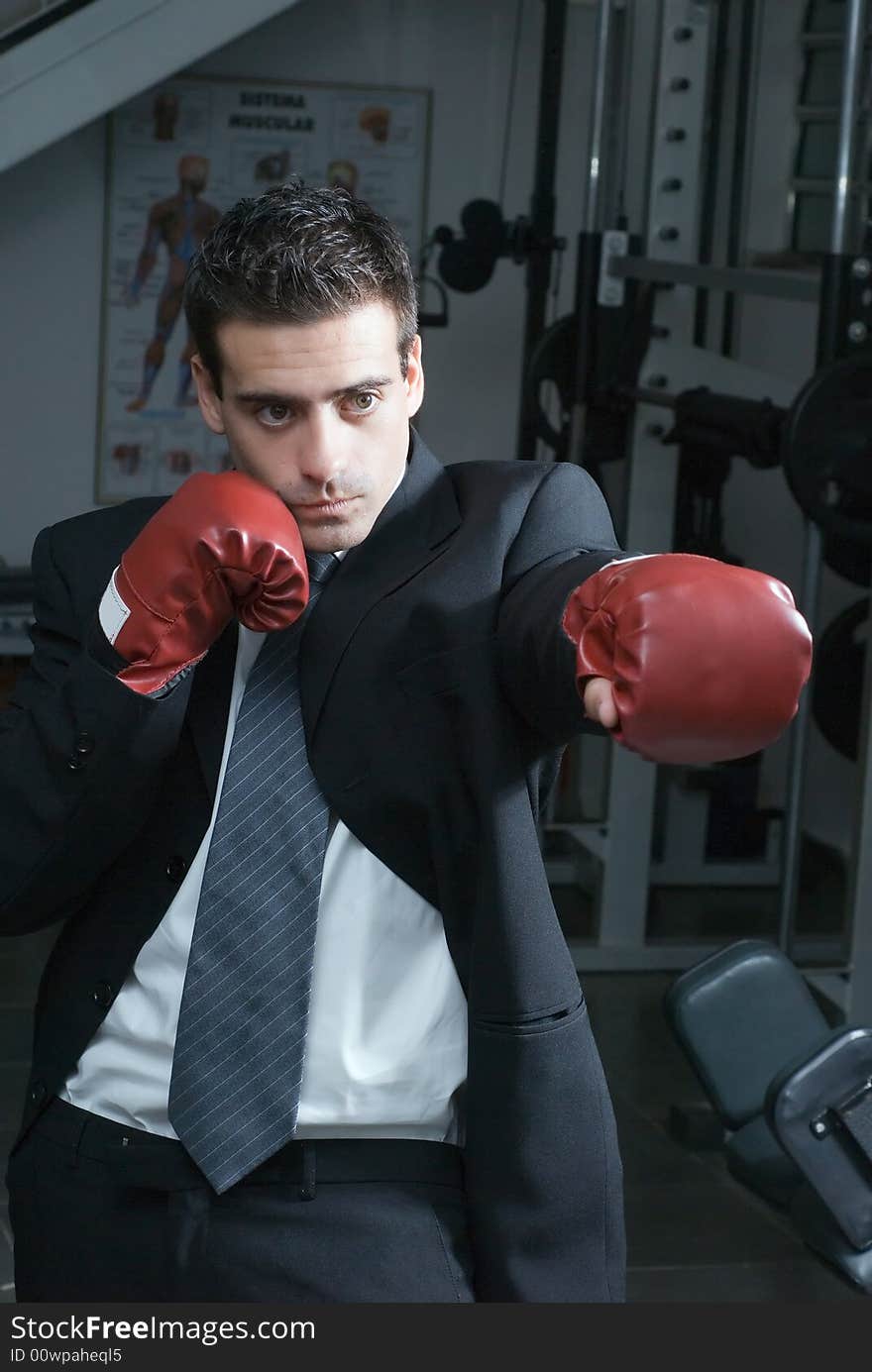 A shot of a businessman, in a gym, wearing boxing gloves. A shot of a businessman, in a gym, wearing boxing gloves.