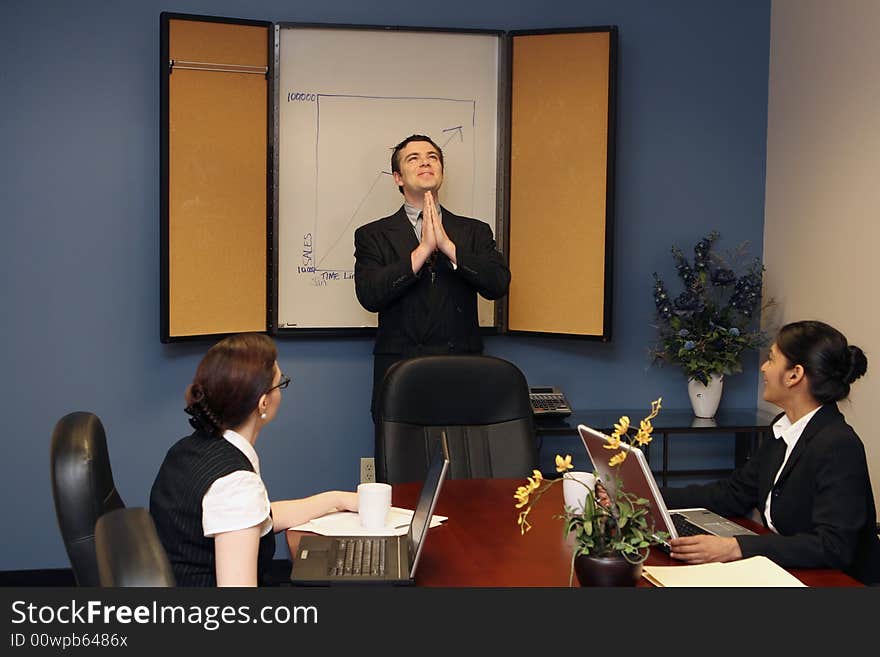 Businessman presenting to his colleagues staring up at the ceiling with his hands joined in prayer. Businessman presenting to his colleagues staring up at the ceiling with his hands joined in prayer