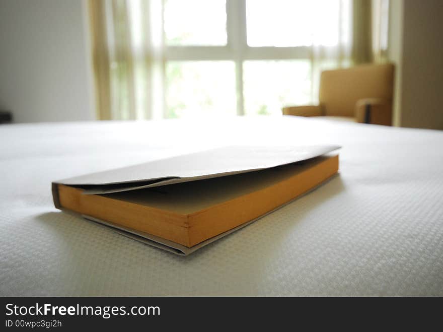 Book on the edge of a neat, white bed. Book on the edge of a neat, white bed.