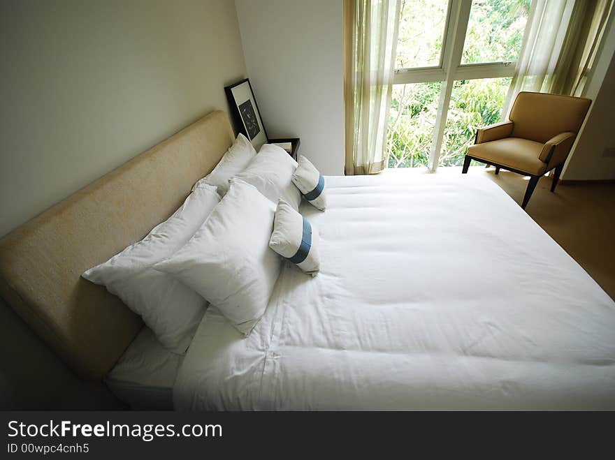 Comfortable bedroom with neatly made white bed. Comfortable bedroom with neatly made white bed.