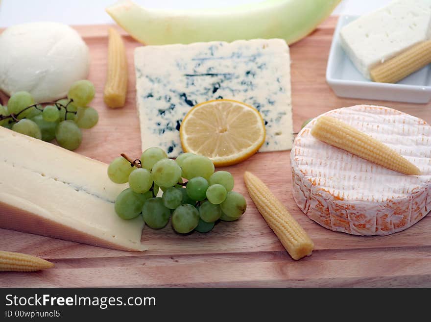 A wodden plate with a lot of different cheeses