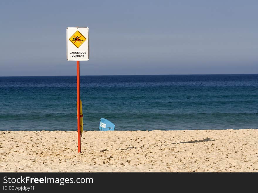 Abandoned lifeguard surf, sign 'dangerous current', on blue clear sky. Abandoned lifeguard surf, sign 'dangerous current', on blue clear sky