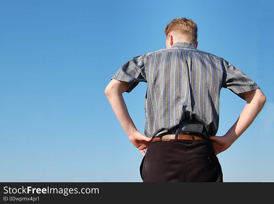 A young man with a gun in his belt, from behind.