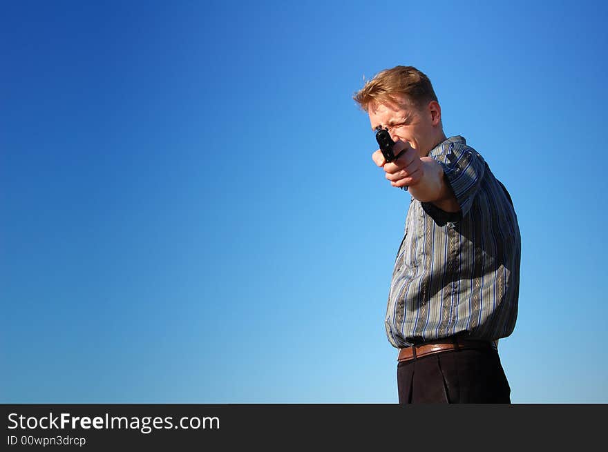 Young man with a gun against blue background. Young man with a gun against blue background