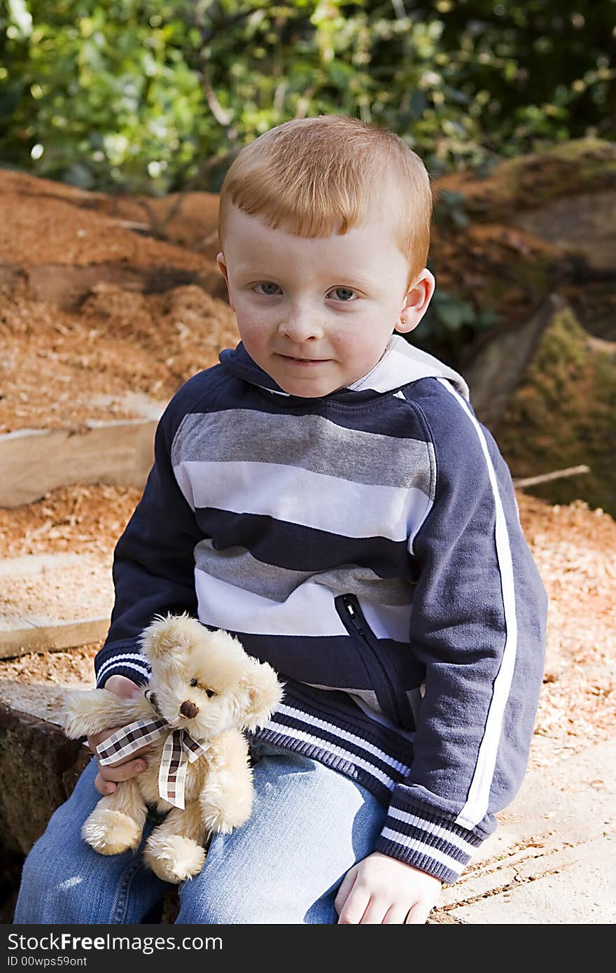 Boy with his teddy bear looking happy and content