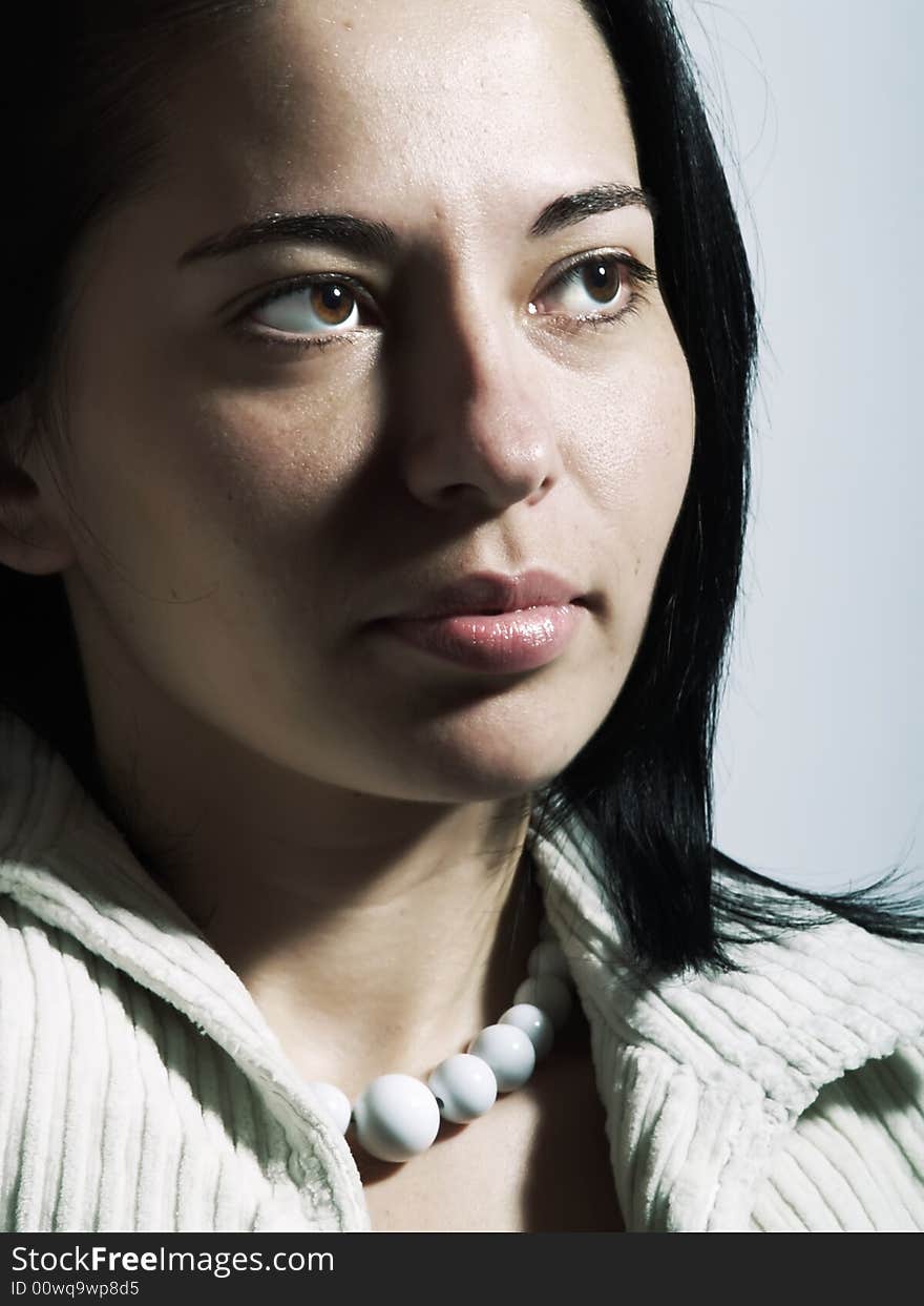 A high-key portrait about an attractive trendy lady with black hair who is looking at something and she has a charming look. She is wearing a white coat and a white necklace. A high-key portrait about an attractive trendy lady with black hair who is looking at something and she has a charming look. She is wearing a white coat and a white necklace.