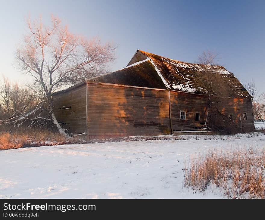 Shadows of trees paint a barn in a winter sunset. Shadows of trees paint a barn in a winter sunset.